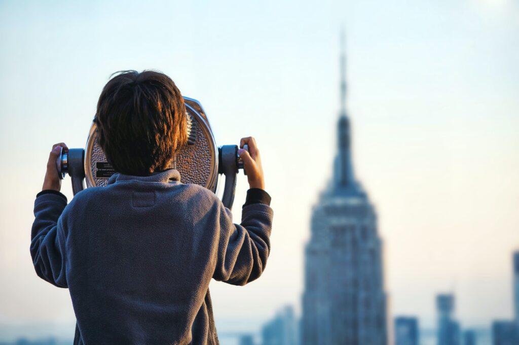 How to spot a great credit card bonus. Child looking at empire state building through fixed binocular stand