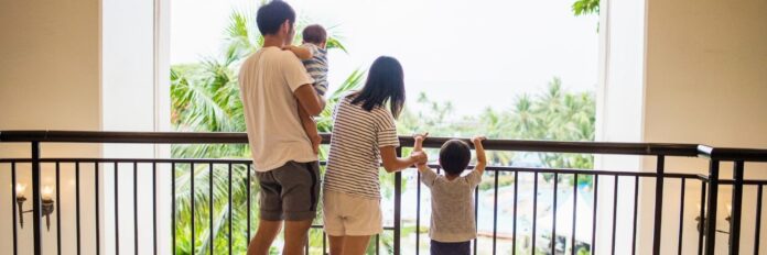 Husbad with Wife and two kids on hotel balcony overlooking hotel pool