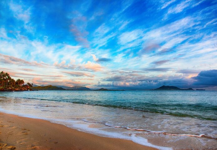 a beach with waves and mountains in the background