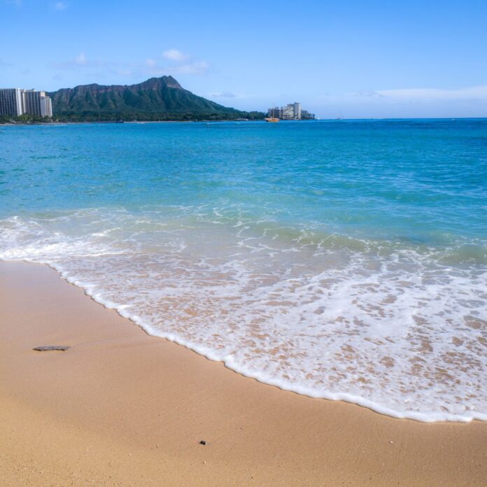 a beach with a body of water and a mountain in the background