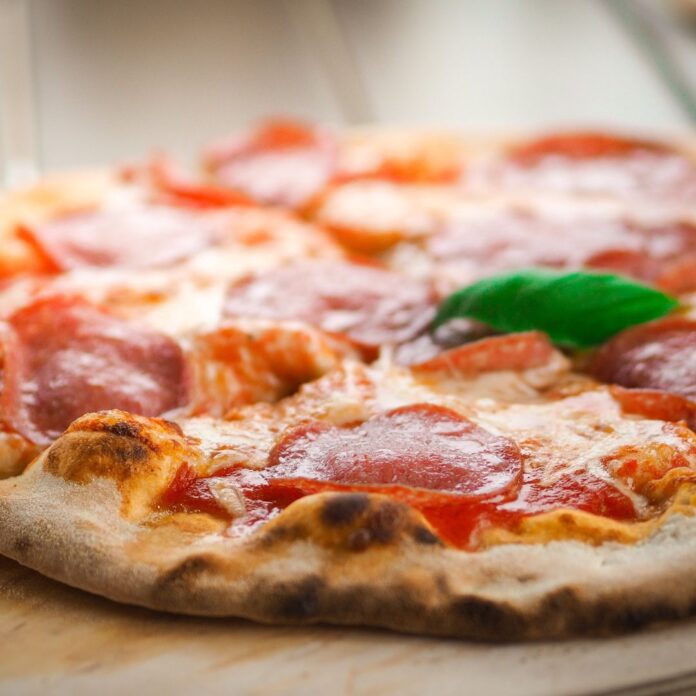 a pizza with pepperoni and cheese on a wood surface