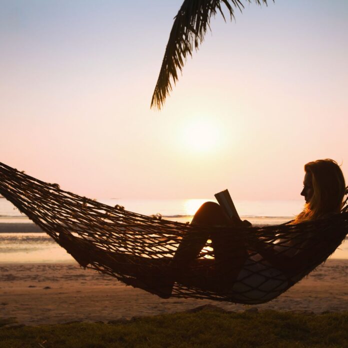 a woman lying in a hammock on a beach