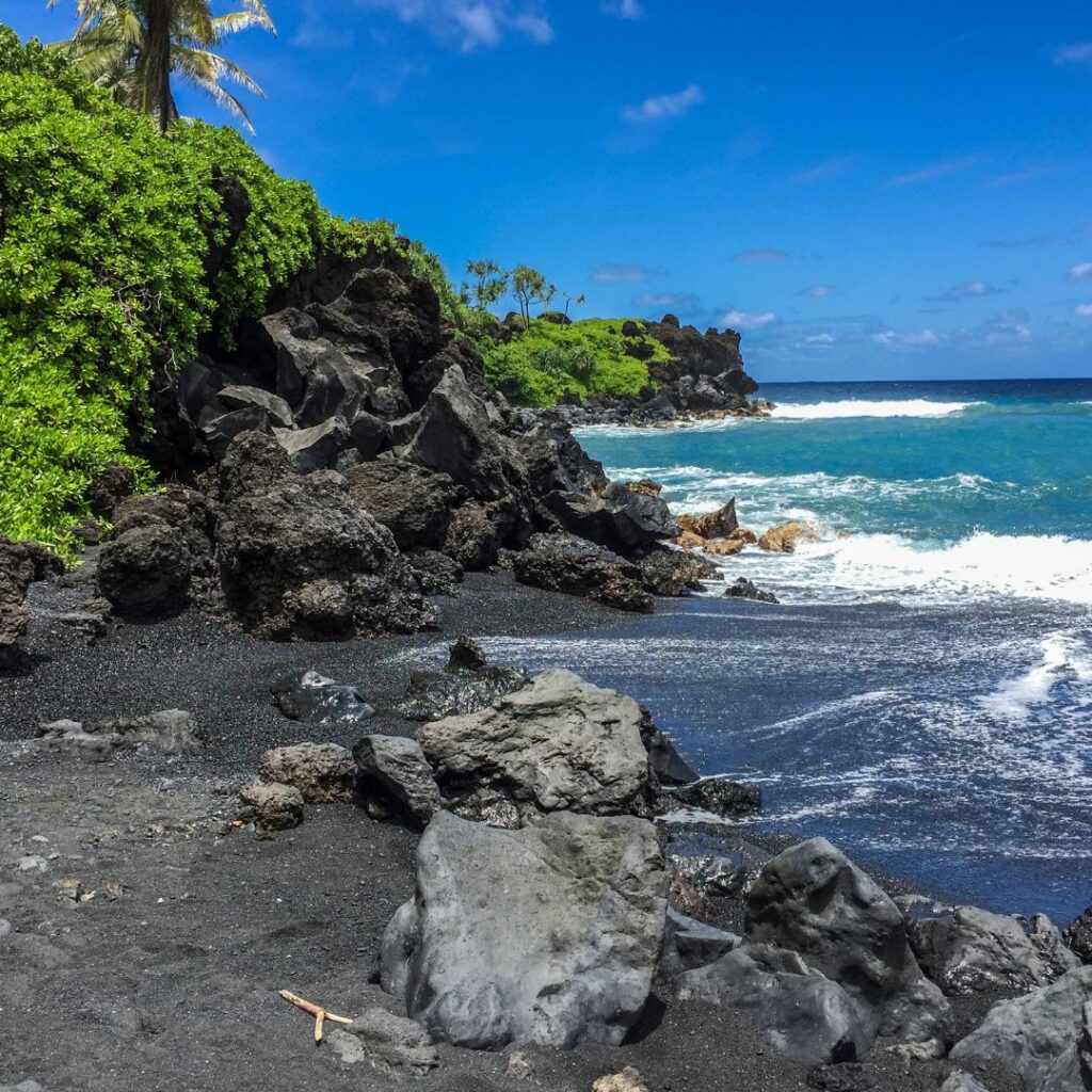 a black sand beach with rocks and water