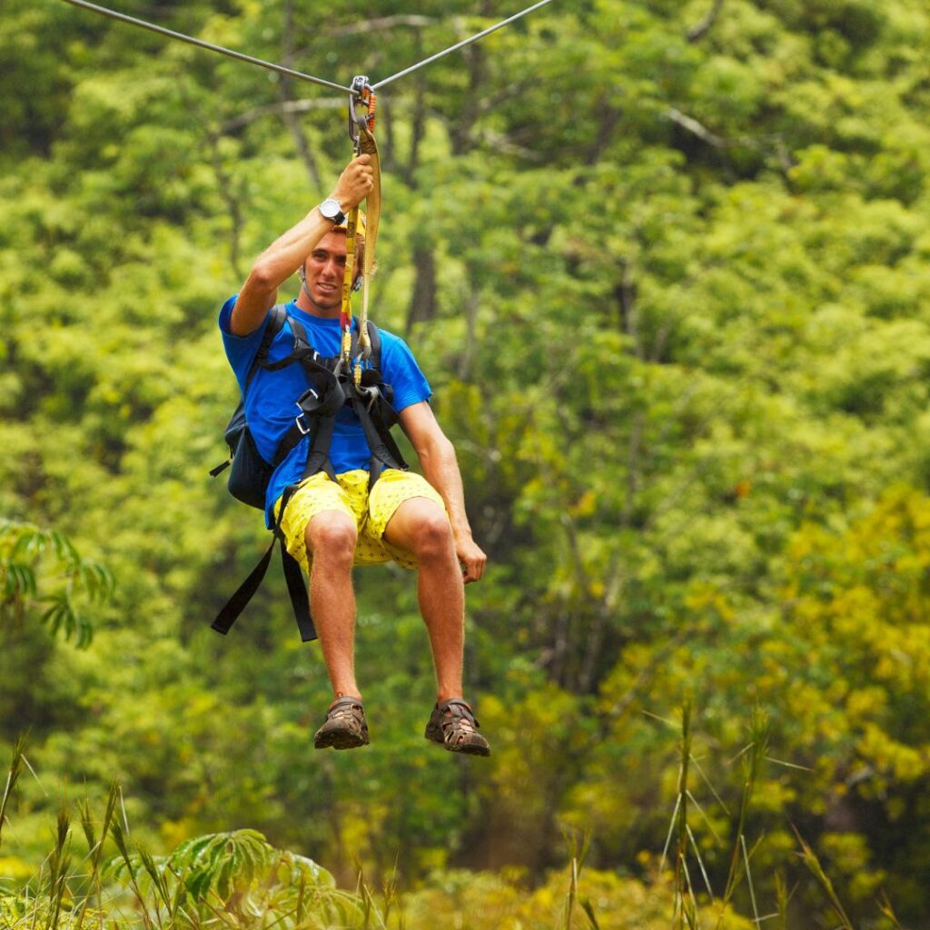 a man in a blue shirt and yellow shorts on a zip line