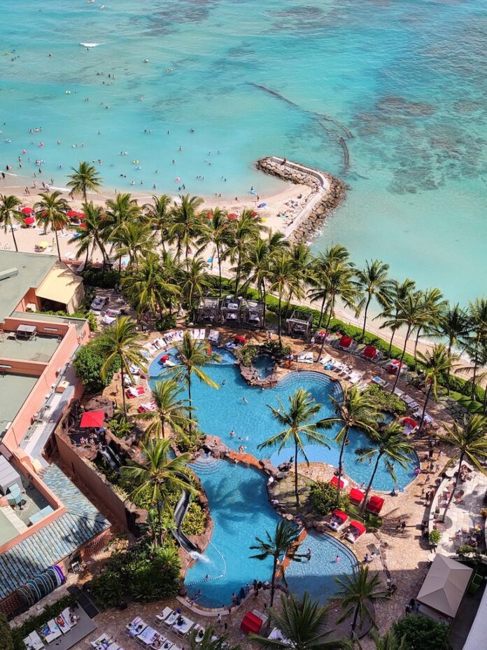a swimming pool with palm trees and people on the beach
