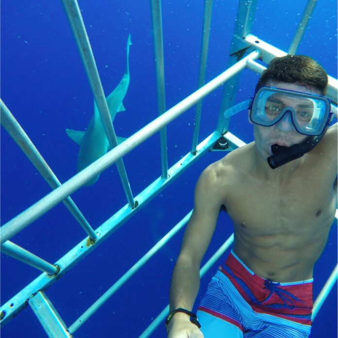 a man wearing snorkeling gear underwater with a shark