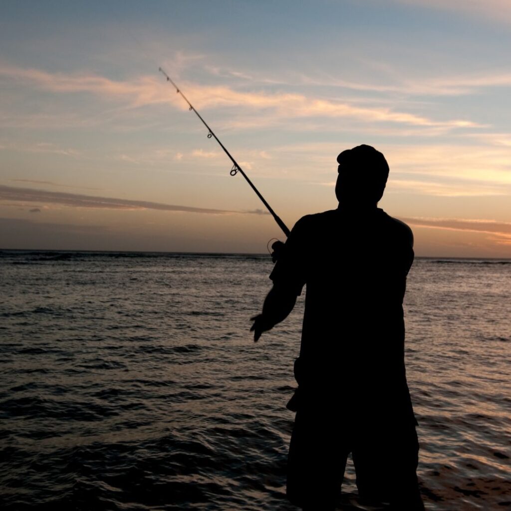 a man standing in the water holding a fishing pole