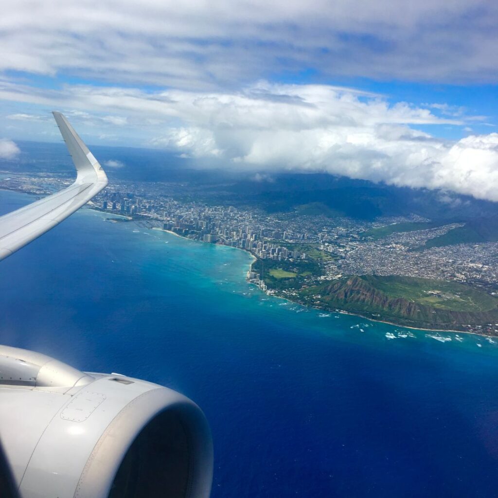 View of Waikiki from an airplane. Many people who want to experience this will be asking, how long are flights to Hawaii? This article will answer this with in-depth detail.