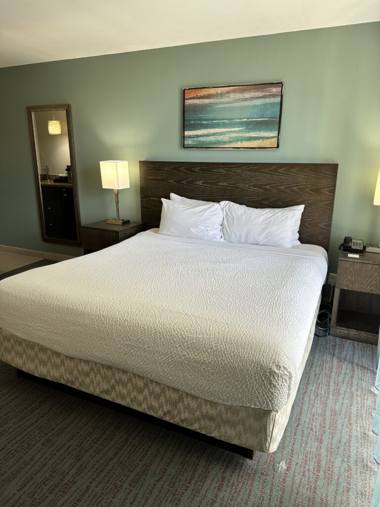 a bed with white sheets and lamps