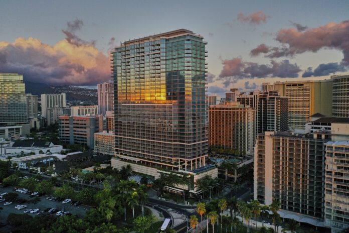 a tall buildings with trees and a road in the background