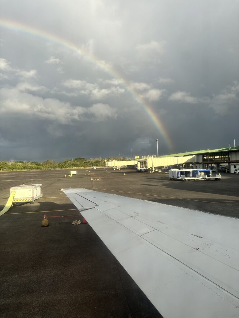 a rainbow over a building and a plane wing