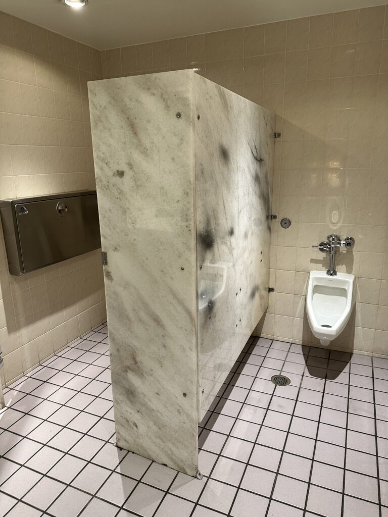 a bathroom with a urinal and a marble wall