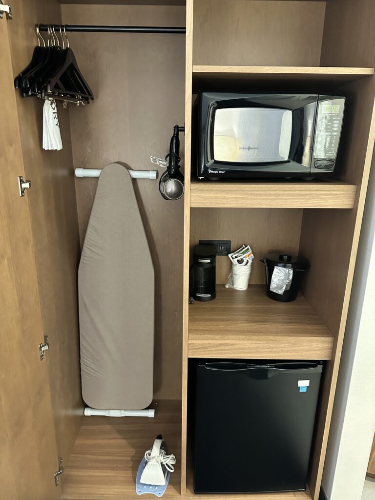 a ironing board and a microwave in a closet