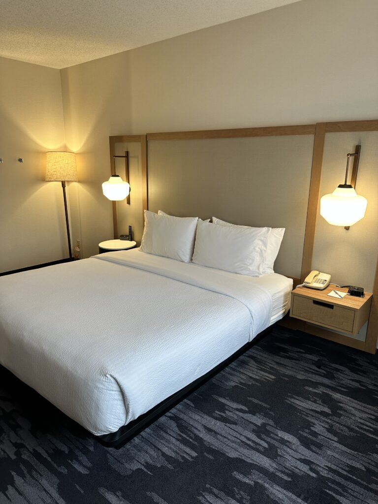 a bed with white sheets and lamps