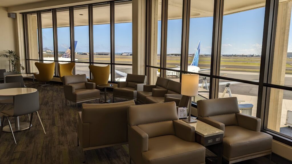 a lounge area with chairs and tables and a lamp