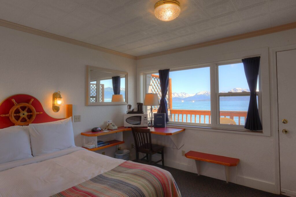 a room with a bed and a desk and a window with a view of the ocean